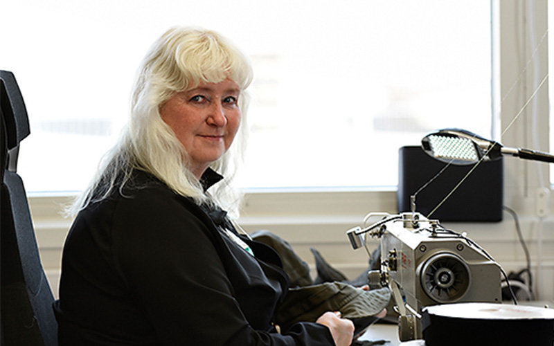 A woman at a sewing machine manufacturing Taiga functional workwear