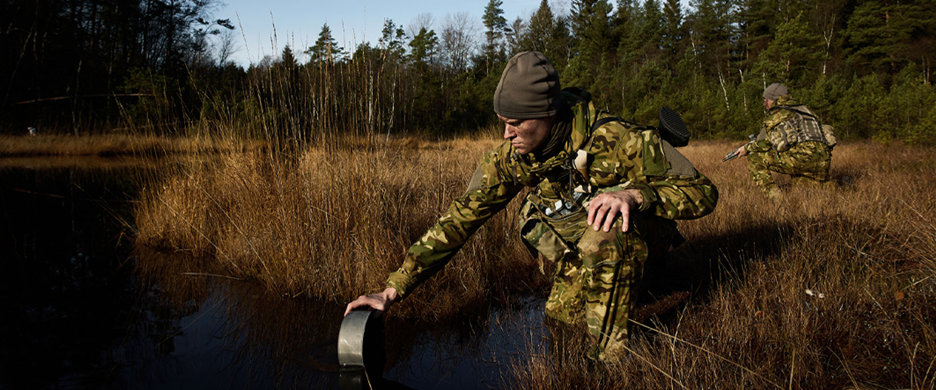 A woman from Tarfala Research Station wearing Taiga workwear near a lake and mountain 